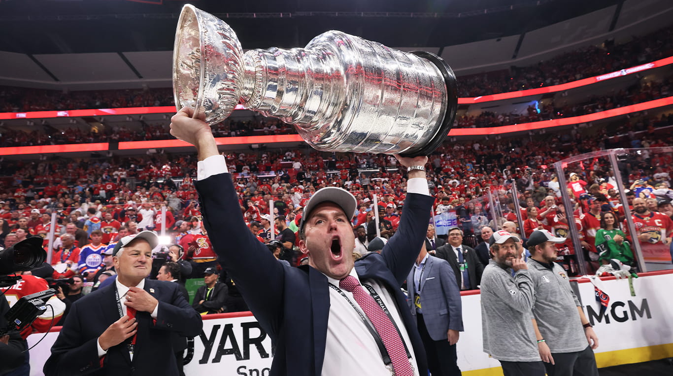 Matt Caldwell celebrates and holds the Stanley Cup over his head, celebrating on the ice after the NHL's Florida Panthers won the 2024 championship.